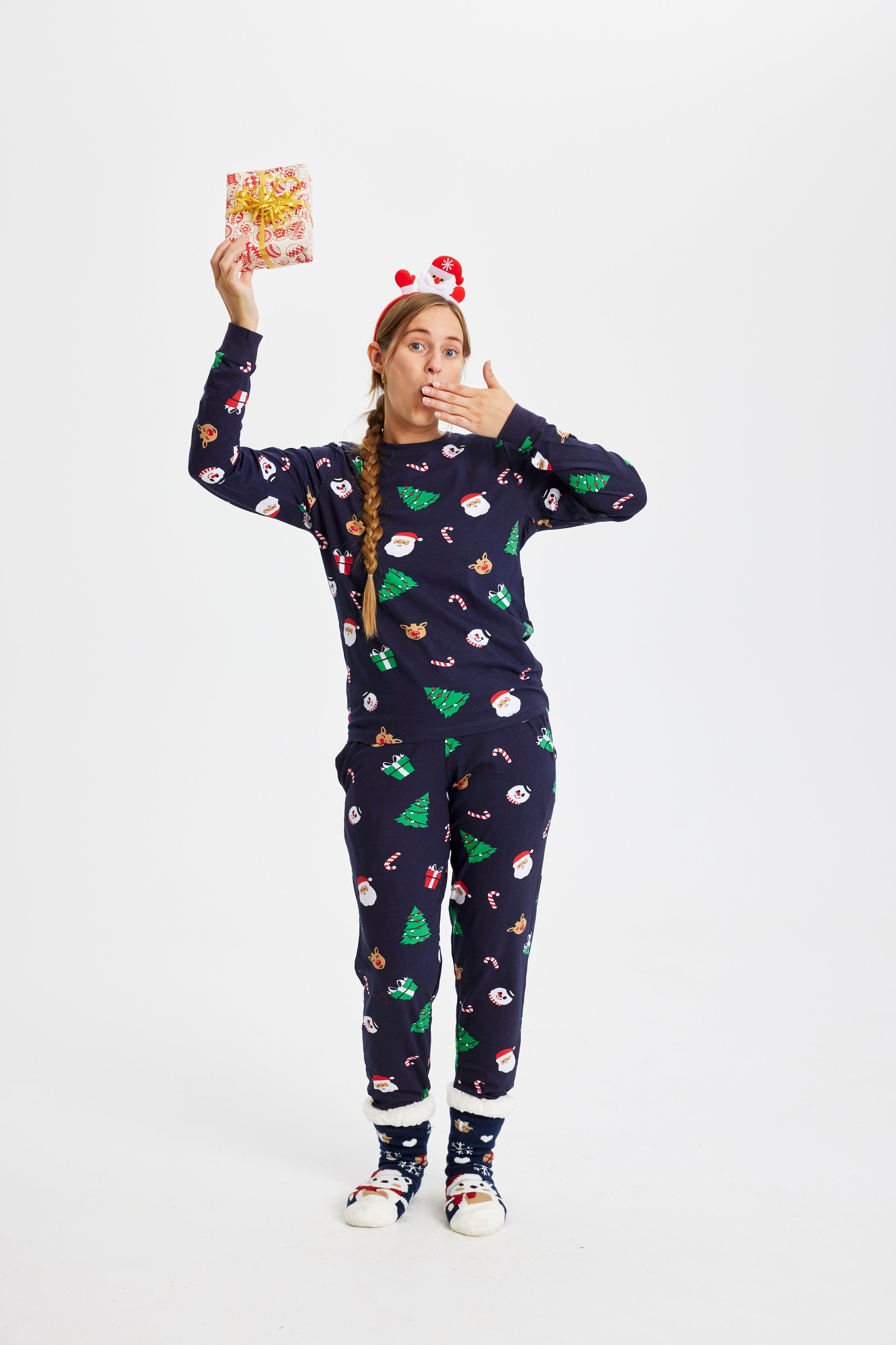 En kvinne i julepyjamas med en gave i hånden.